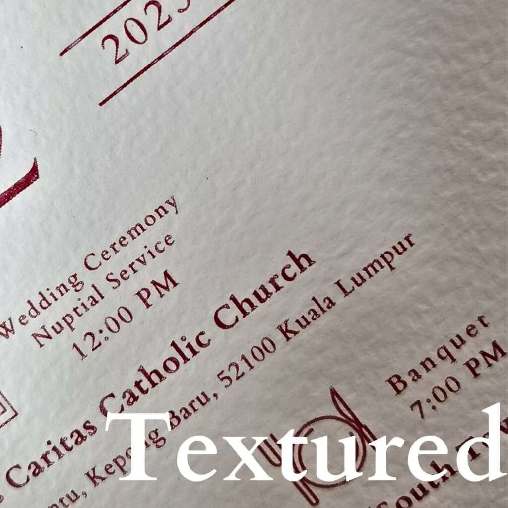 Close-up view of a textured card with richly printed details of a wedding ceremony and venue.