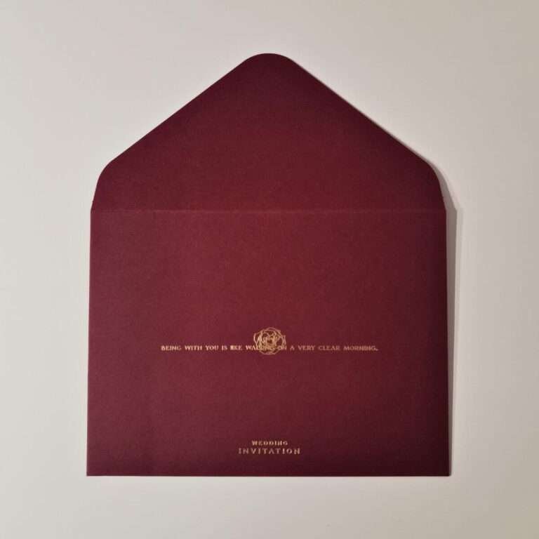 Front view of a Classic Rose Wine Red Wedding Invitation Envelope with gold embossed lettering and decorative emblem from Xamiya Wedding.